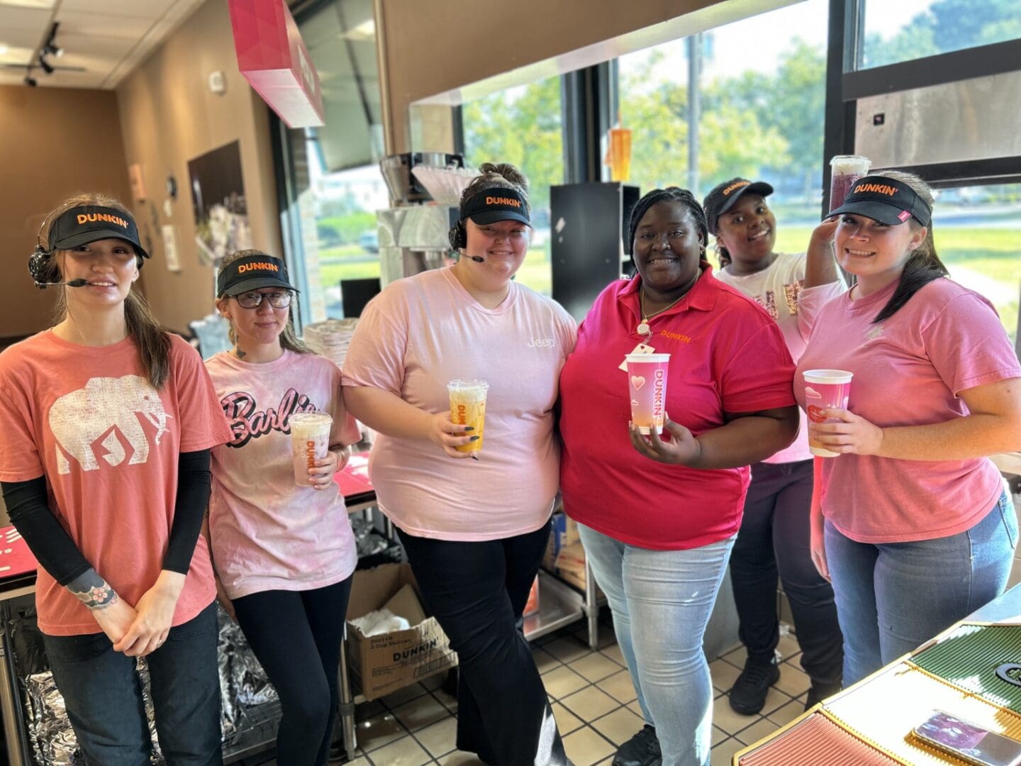 Dunkin staff smiling holding iced drinks